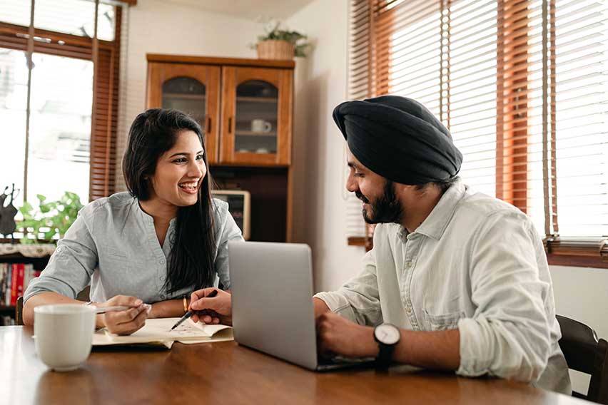 2 people sitting at a table looking at a laptop