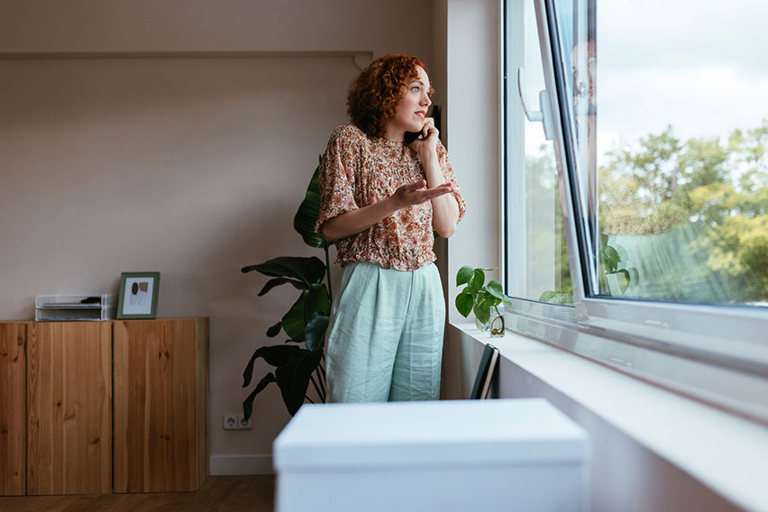 person standing at a window talking on a mobile phone